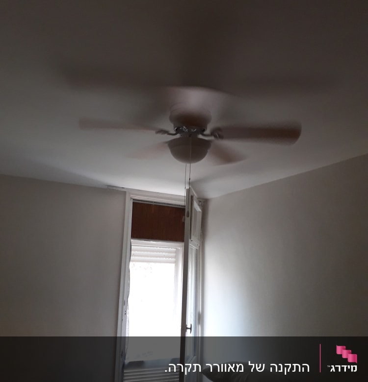 מאוורר תקרה מסתובב בחדר עם חלון פתוח